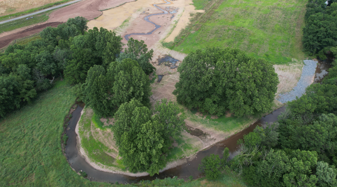 drone view of stream restoration project with green trees and winding stream